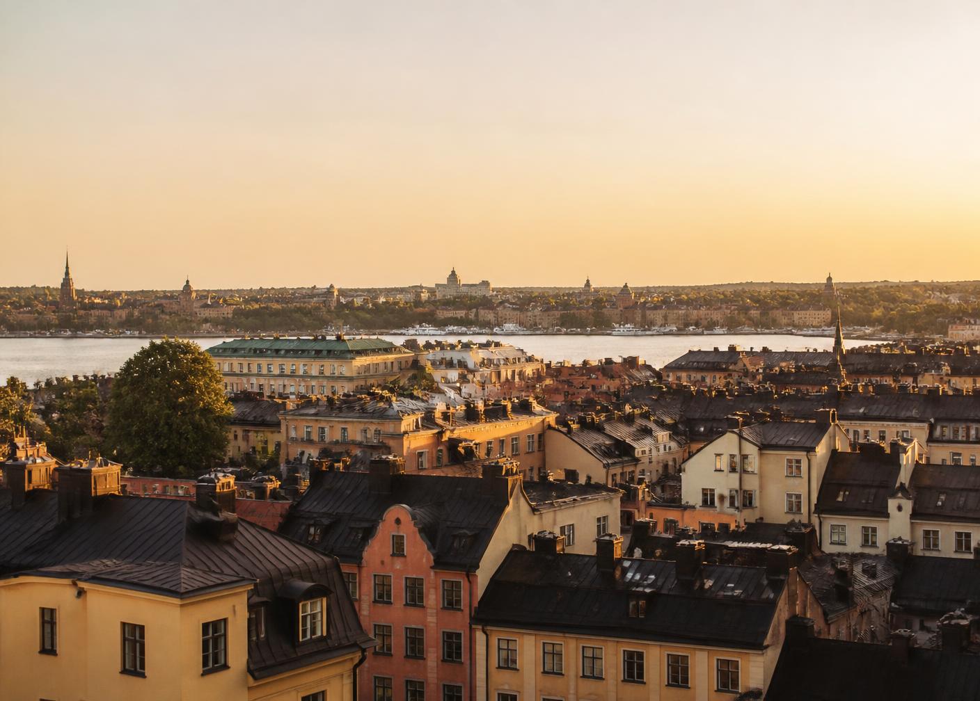Utsikt över Stockholms tak och vatten i varmt kvällsljus